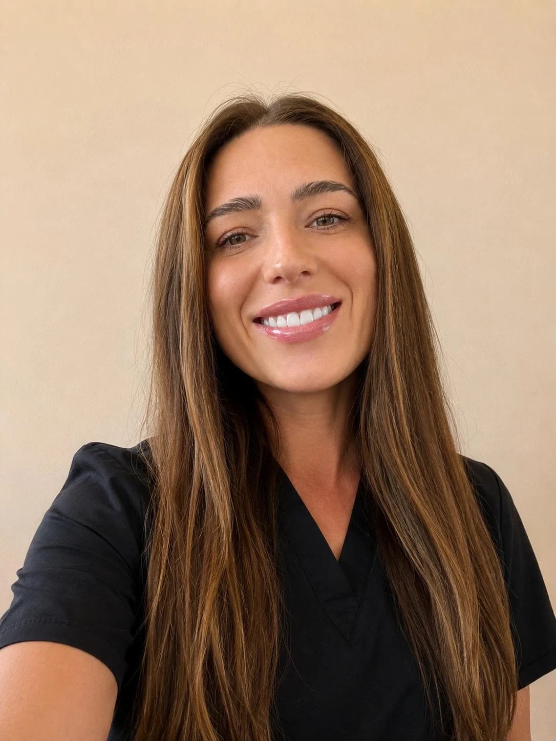 Staff member smiling, wearing black scrubs with long hair down